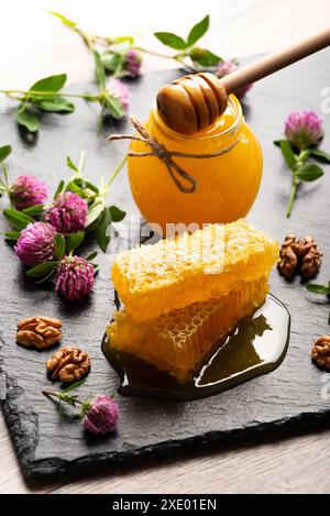 Nid d'abeille sur plateau en ardoise avec miel et noix sur la table de cuisine Banque D'Images