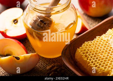 Pot Mason avec un pot au miel et des pommes rouges et un nid d'abeille sur une table de cuisine Banque D'Images