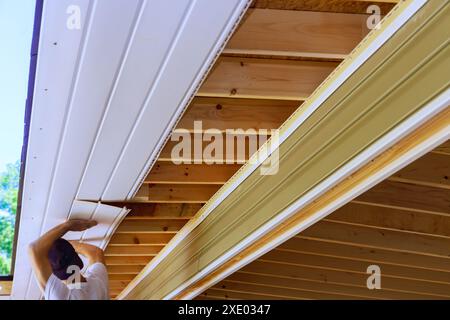 Les planches de soffite en plastique sont montées sur les chevrons de toit du plafond de la maison Banque D'Images