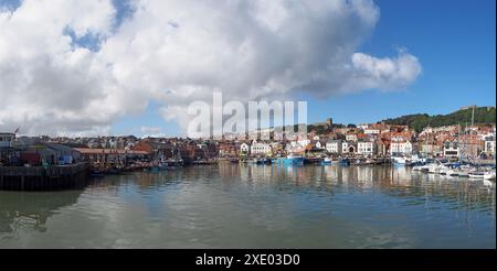 Longue vue panoramique sur le port de scarborough un jour d'été avec des bateaux de pêche reflétés dans l'eau et les bâtiments de la ville Banque D'Images