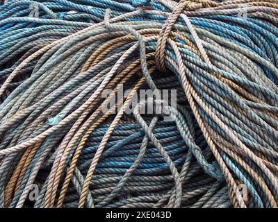 Pile de vieille corde de pêche marine enroulée et nouée bleue dans les tons de bleu et de brun Banque D'Images