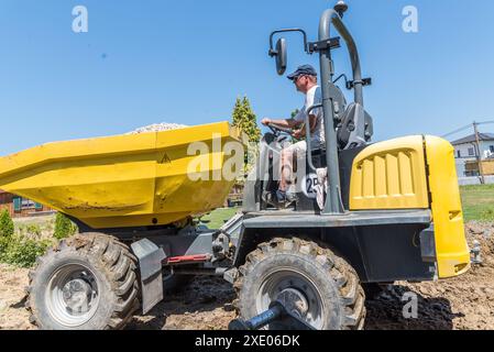Travailleur de la construction conduit sur le chantier de construction avec dumper - véhicule de construction Banque D'Images