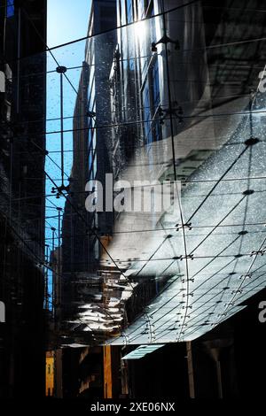Regardant à travers un auvent de panneaux de verre, un plafond de verre au-dessus de la place Aurora place sur Phillip Lane, ombres, formes géométriques, reflets. Banque D'Images