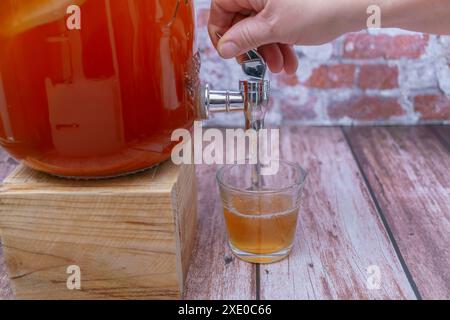 Ouvrir le robinet d'une bouteille de thé kombucha fermenté Banque D'Images