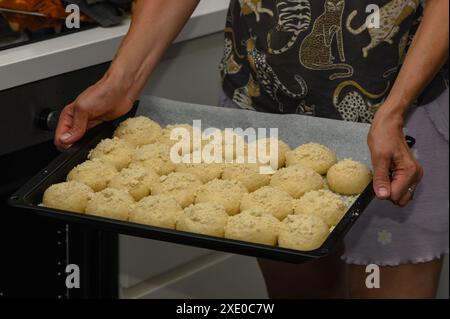 femme met les petits pains dans le four sur une plaque de cuisson Banque D'Images