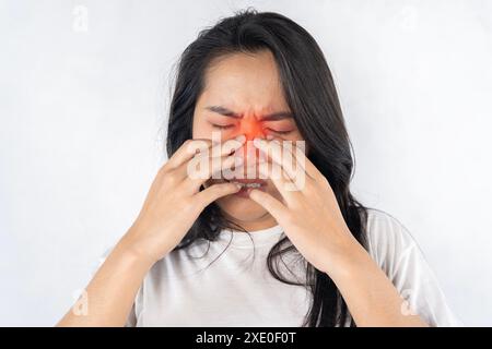Une femme au nez et aux yeux rouges se frotte le nez. Elle souffre et souffre d'un rhume Banque D'Images
