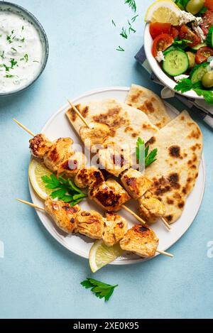 Kebabs souvlaki au poulet, sauce yaourt aux herbes et pain pita flatbread en gros plan. Repas méditerranéen sain - brochettes de viande maison et salade verte oraganique Banque D'Images