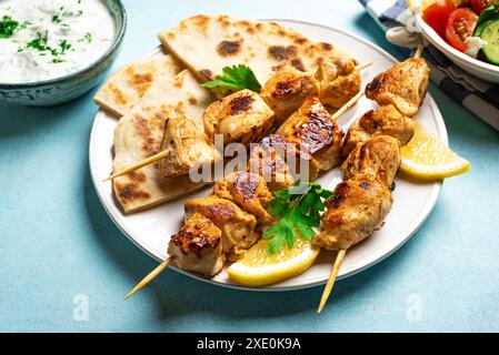 Kebabs souvlaki au poulet, sauce yaourt aux herbes et pain pita flatbread en gros plan. Repas méditerranéen sain - brochettes de viande maison et salade verte oraganique Banque D'Images