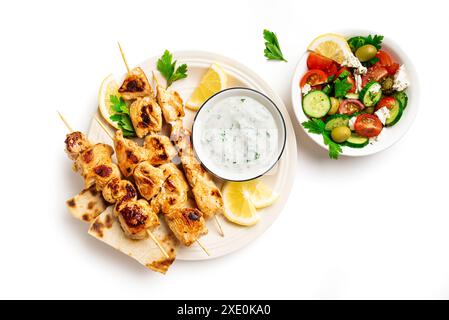 Brochettes grillées de souvlaki, salade grecque et sauce tzatziki sur assiette isolé sur fond blanc, vue de dessus. Déjeuner grec méditerranéen avec kebabs à viande, Banque D'Images