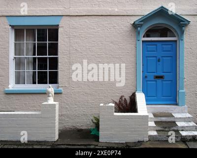 Vue de face d'une vieille maison en brique anglaise typique, petite maison en terrasses, mur peint en blanc et porte bleue Banque D'Images