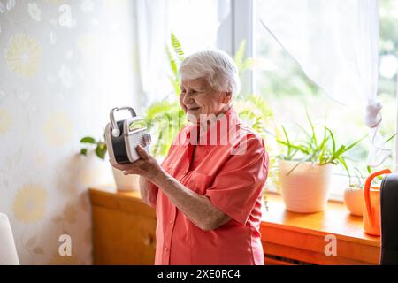 Femme âgée souriante écoutant la radio à la maison Banque D'Images