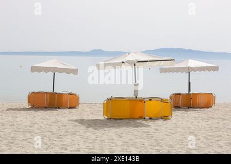 Parasols blancs avec des chaises de plage jaunes et orange sur une belle plage de sable, pas de gens Banque D'Images