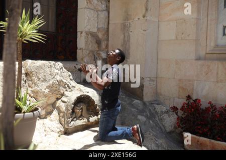 Homme nigérian, musulman, converti au christianisme pentecôtiste s'agenouille sur le rocher de l'agonie dans le jardin de Gethsémani prie exubéramment avec les mains et le visage vers le haut Banque D'Images