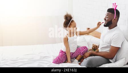 Petite fille appliquant du rouge à lèvres sur ses lèvres de Pères Banque D'Images