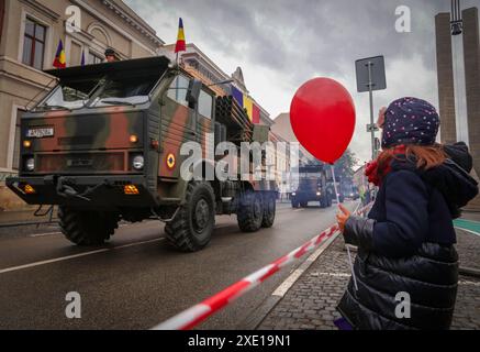 Une jeune fille a regardé passer un véhicule militaire blindé pendant le défilé de la Grande Union à Cluj-Napoca, en Roumanie Banque D'Images