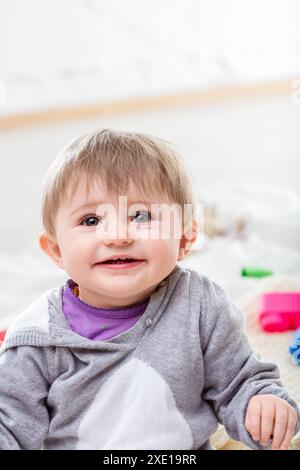 Joyeuse petite fille joue joyeusement entourée de jouets colorés, exsudant l'innocence et le bonheur. Elle regarde la caméra, incarnant l'amour de la famille et les soins moi Banque D'Images