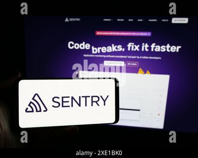 Personne tenant un smartphone avec le logo de la société américaine Functional Software Inc (Sentry) devant le site Web. Concentrez-vous sur l'affichage du téléphone. Banque D'Images