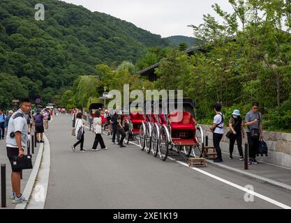 Tokyo, Japon. 25 juin 2024. Les touristes attendent pour monter à bord de la charrette Jinrikisha dans le quartier Arashiyama de Kyoto. Le pousse-pousse japonais ou Jinrikisha est un transport traditionnel par chariot avec un guide qui le tire autour, servant comme un autre symbole emblématique du Japon et populaire parmi les touristes. Crédit : SOPA images Limited/Alamy Live News Banque D'Images