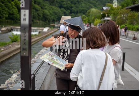 Tokyo, Japon. 25 juin 2024. Un cavalier de pousse-pousse communique avec les touristes dans la région d'Arashiyama à Kyoto. Le pousse-pousse japonais ou Jinrikisha est un transport traditionnel par chariot avec un guide qui le tire autour, servant comme un autre symbole emblématique du Japon et populaire parmi les touristes. Crédit : SOPA images Limited/Alamy Live News Banque D'Images