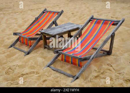 Deux chaises longues en bois colorées sur la plage de sable Banque D'Images