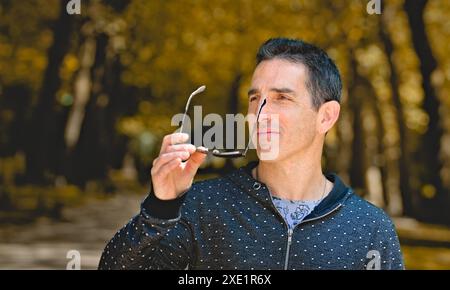 Homme méditerranéen dans des vêtements de sport décontractés enlevant les lunettes de soleil. Banque D'Images