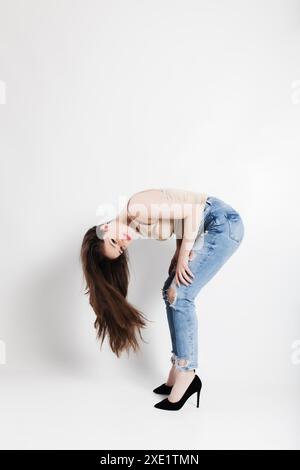 Portrait dynamique d'une jeune mannequin faisant un backbend tout en étant habillé dans un style chic décontracté avec un Jean denim et des talons noirs, montrant la flexibilité Banque D'Images