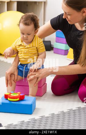 Réadaptation des traumatismes de la naissance. Physiothérapeute aidant le bébé à développer ses habiletés motrices pendant la séance de thérapie Banque D'Images