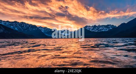 Vue majestueuse grand angle sur les montagnes rocheuses couvertes de neige près d'un lac sous un ciel nuageux coucher de soleil Banque D'Images