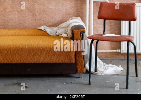 Vieux canapé avec chaise dans une maison abandonnée Banque D'Images