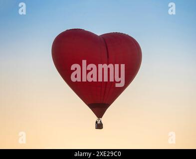 Montgolfière en forme de coeur rouge au fond de ciel de coucher de soleil Banque D'Images
