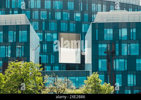 Extérieur commercial en verre moderne de l'architecture d'immeuble de bureaux. Bâtiment abstrait couvert de fenêtres avec des arbres verts à l'avant. Co Banque D'Images