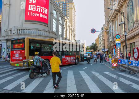 Harbin, Chine - 17 juin 2024 : paysage urbain, passage piétonnier sur lequel les gens marchent, un bus et un scooter roulent le long de la route. Photo de haute qualité Banque D'Images