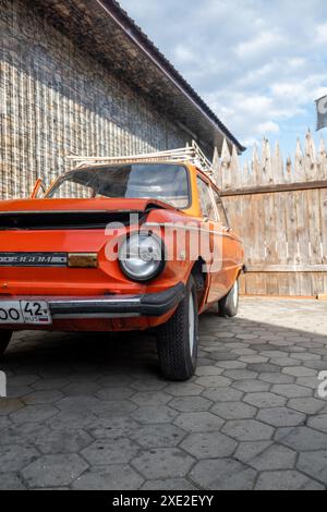 Rouge vieille voiture Zaporozhets dans la cour par une journée ensoleillée. Banque D'Images