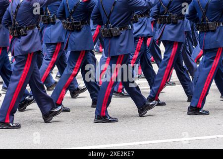 Oviedo, Espagne - 25 mai 2024 : un groupe de soldats armés sur une parade militaire marchant à l'unisson dans un uniforme bleu avec des bandes rouges sur une route asphaltée Banque D'Images