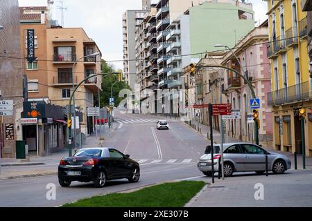 Figueres, Espagne - 14 mai 2023 : une rue à Figueres, Espagne, avec des voitures qui descendent une rue bordée de bâtiments et de magasins. Le temps est ensoleillé. Banque D'Images