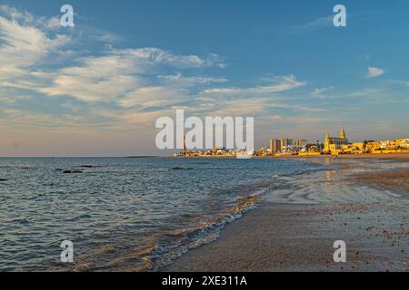 Plage de Regla avec église et phare à Chipiona dans la lumière chaude du soir Banque D'Images
