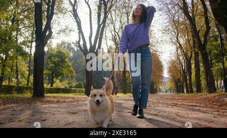 Caucasien jeune femme fille propriétaire d'animal domestique femme foulée avec chien chiot en laisse marchant dans la ville heureux petit chien mignon gallois corgi courir rue dans Banque D'Images