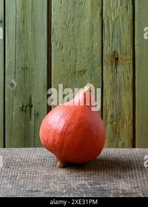 Red Kuri ou Uchiki Kuri Squash ou Hokkaido citrouille sur une vieille table en bois avec fond vert et espace de copie Banque D'Images