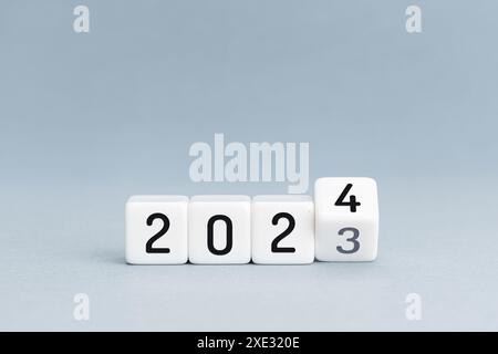 Concept du nouvel an. Passez de 2023 à 2024 blocs cubes isolés sur fond bleu. Espace de copie Banque D'Images
