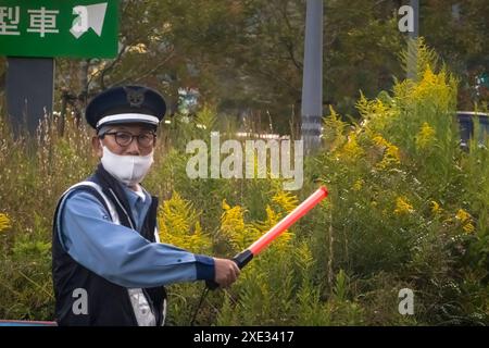 Yamanakako, préfecture de Yamanashi, Japon. 5 novembre 2023. Gros plan sur un agent de transit contrôlant le trafic tout en portant un visage mas Banque D'Images