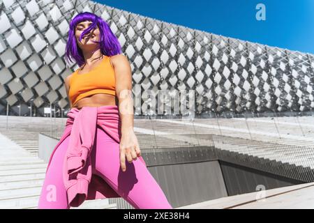 Danseuse femme active insouciante portant des vêtements de sport colorés s'amusant dans la rue Banque D'Images