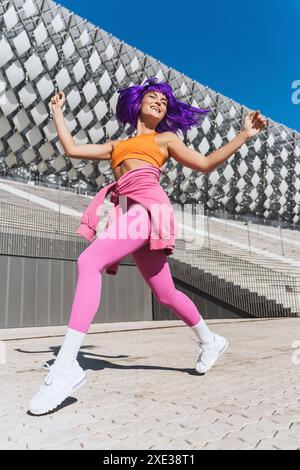 Danseuse femme active insouciante portant des vêtements de sport colorés s'amusant dans la rue Banque D'Images