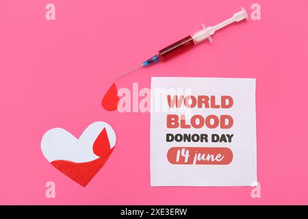 Composition avec coeur en papier, goutte, seringue et feuille de papier avec texte WORLD BLOOD DONOR DAY 14 JUIN sur fond rose Banque D'Images