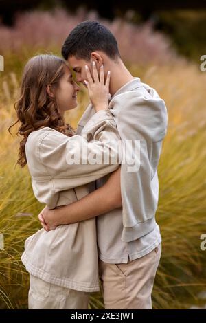 Couple heureux sur la promenade d'automne à l'extérieur. Deux amoureux dans le parc d'automne. Amour et toucher tendre. Câlins doux. Jeune homme et jeune femme en clas Banque D'Images
