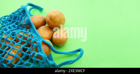 Sac à provisions réutilisable String, sac ouvert en filet avec pommes de terre. Sac à provisions en maille avec des légumes sur gr Banque D'Images