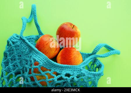 Sac à provisions réutilisable, sac en filet ouvert avec pommes fraîches. Sac à provisions en maille avec des fruits sur gr Banque D'Images