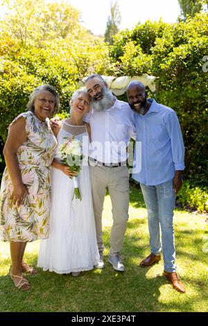 Célébration du mariage, amis seniors tenant un bouquet de fleurs et posant à l'extérieur Banque D'Images