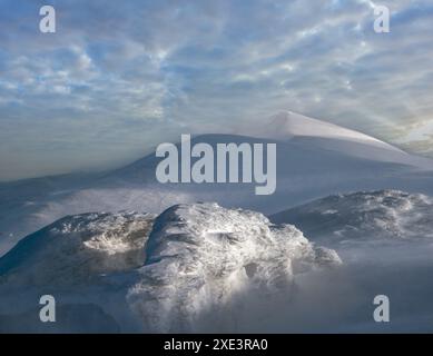 La neige couvrait les montagnes d'hiver en plein soleil le soir dernier. Magnifique crépuscule venteux sur les sommets au-dessus de la pittoresque station de ski alpin Banque D'Images