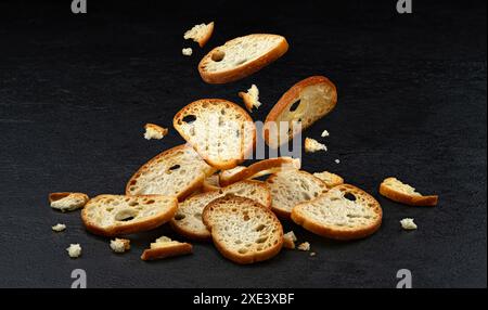 Craquelins bruschetta tombant, croûtons de pain rond isolés sur fond noir Banque D'Images