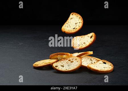 Craquelins bruschetta tombant, croûtons de pain rond isolés sur fond noir Banque D'Images